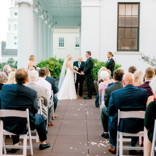 Bride & Groom with minister in front of group of people